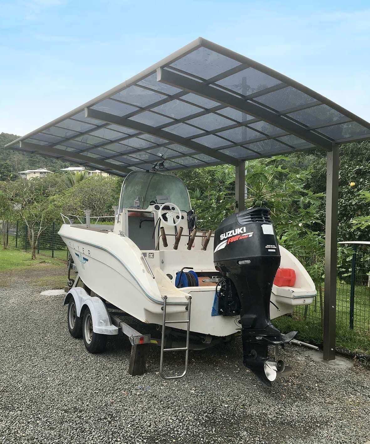 Un bateau est garé sous un auvent dans un terrain en gravier.