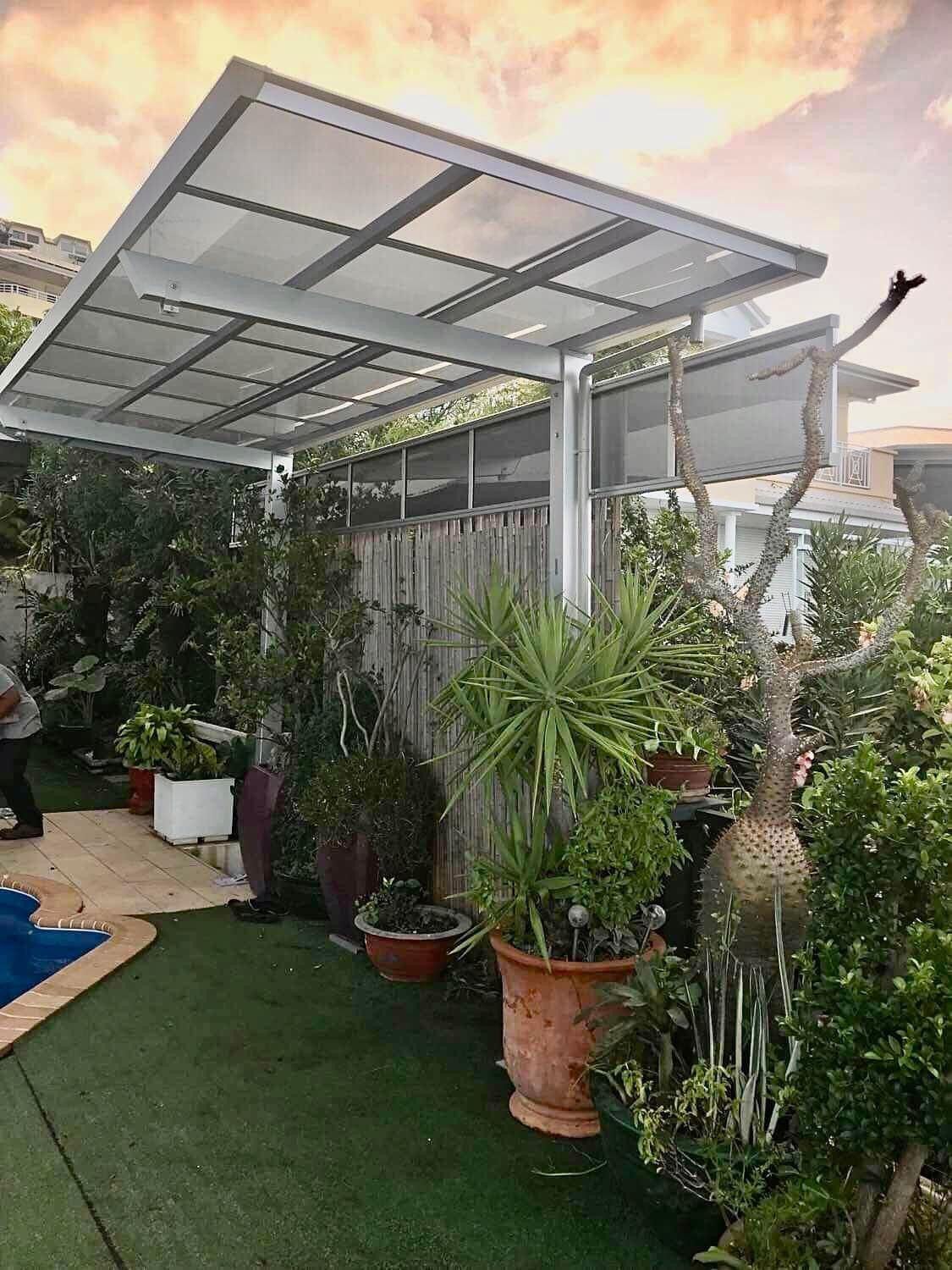 Un jardin avec beaucoup de plantes en pot et un auvent.