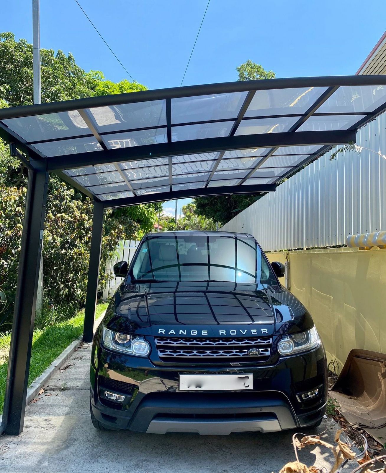 Un Range Rover Sport noir est garé sous un abri voiture.