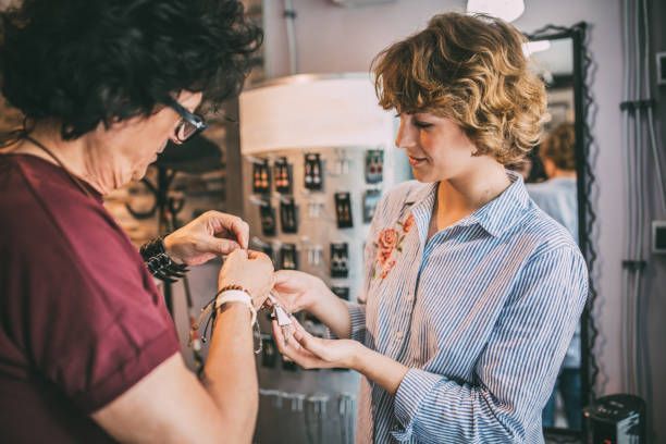 Woman presenting jewelry to a store buyer, focusing on a necklace, close-up view. 