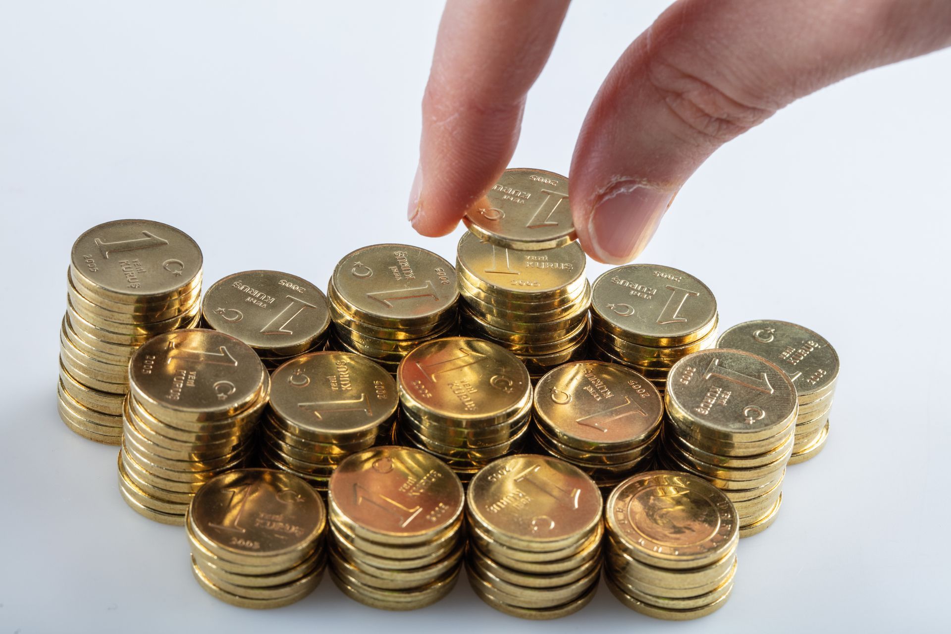 A hand arranging a pile of gold coins, illustrating the process of a coin seller at work.