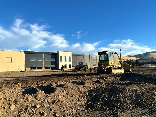 Construction site with a bulldozer and building under construction; blue sky.