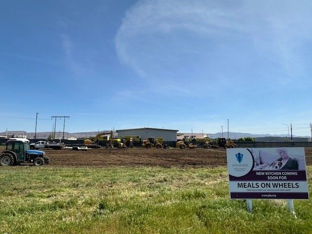 Field with construction equipment; sign promotes 