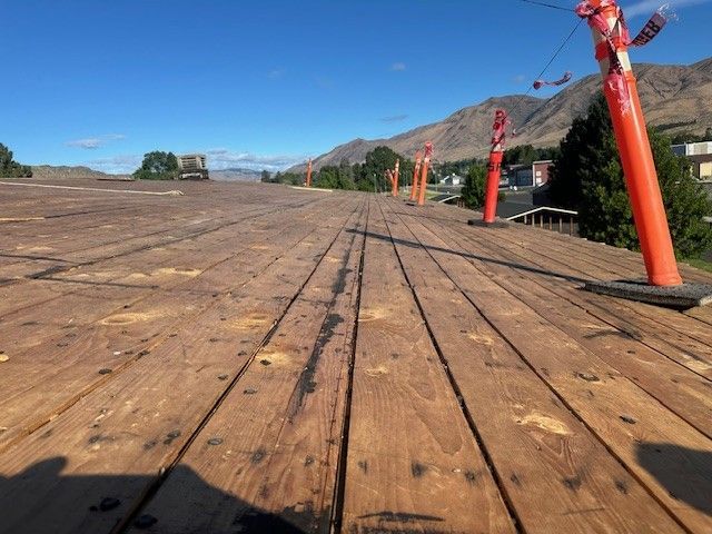 Wooden boardwalk with orange poles, leading to a distant mountain view under a blue sky.