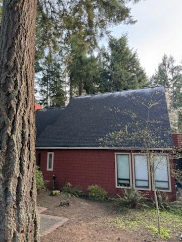 Red house with a dark roof surrounded by trees.