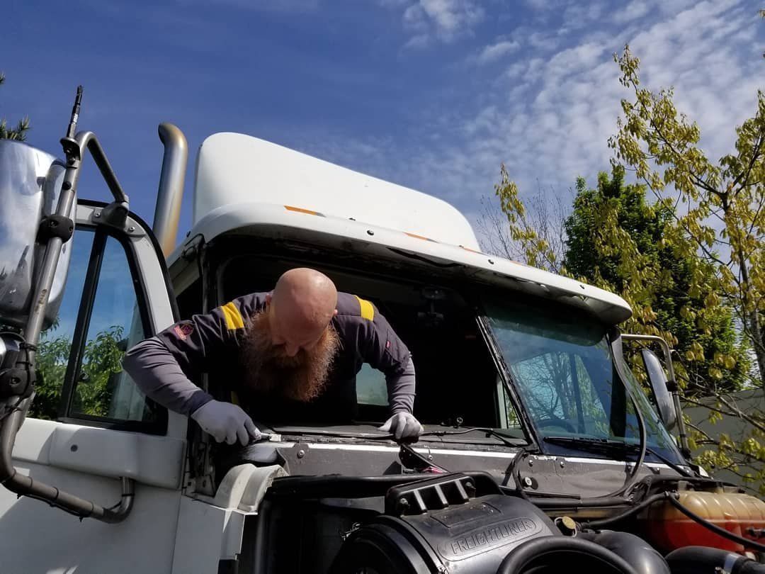 A Man Is Working on the Windshield of a Semi-truck - Renton, WA - Good Dog Auto Glass