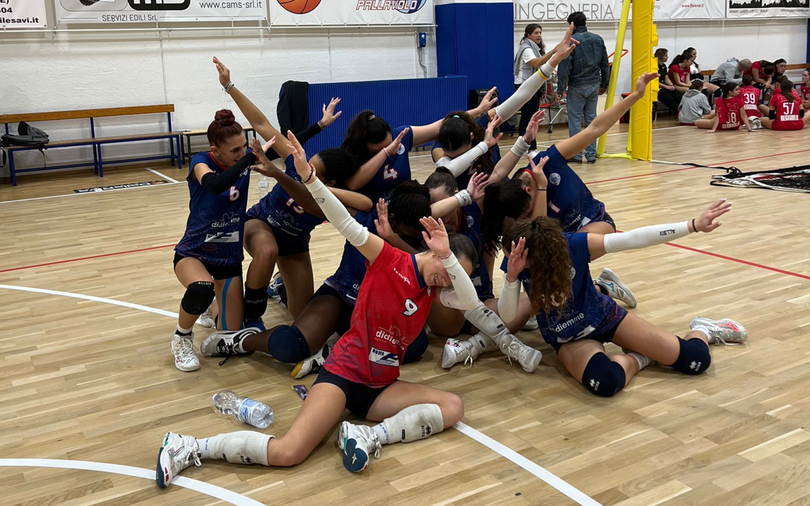 Un gruppo di bambini e adulti sta lanciando palloni da basket in una palestra. I giocatori indossano uniformi rosse e blu e sembrano divertirsi.