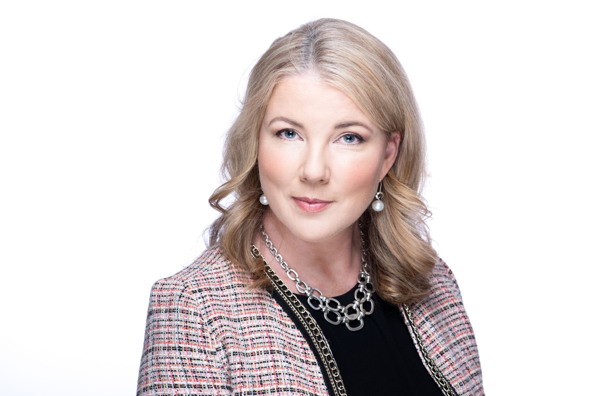 A woman wearing a jacket and a necklace is standing in front of a white background - Carmen & Co Consulting Strategic Consulting in Southeast Queensland