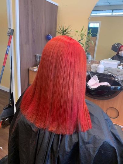 A woman with red hair is getting her hair cut in a salon.