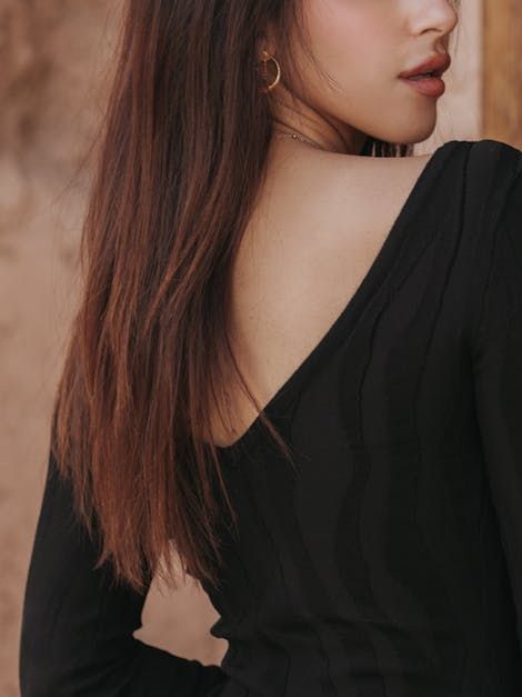 A woman is wearing a black dress with a v-neck and long sleeves.