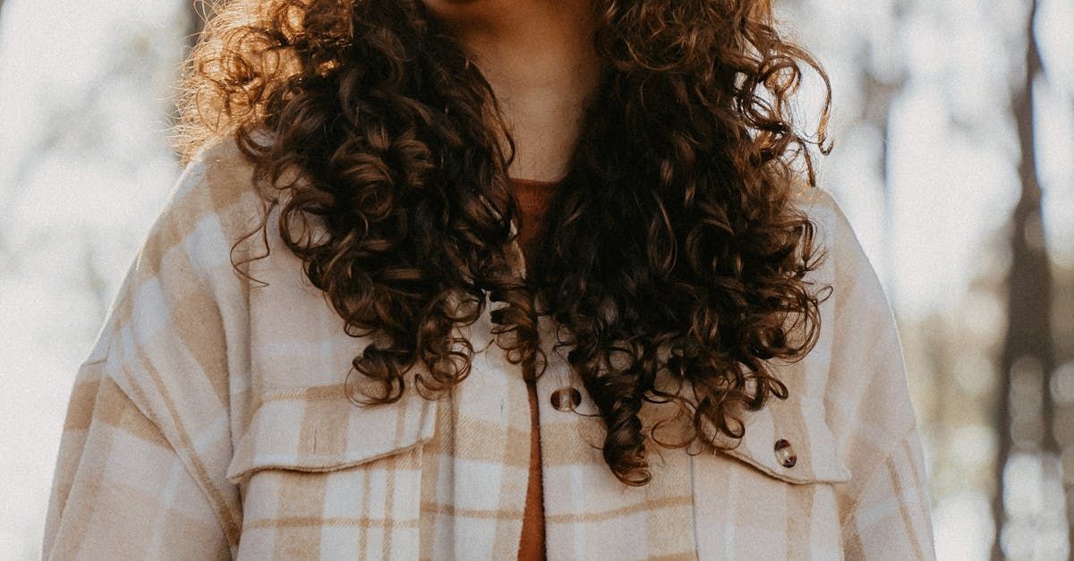 A woman with curly hair is wearing a plaid jacket.