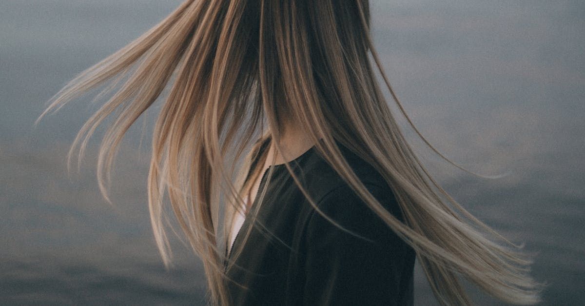 A woman with long hair is standing in front of a body of water.