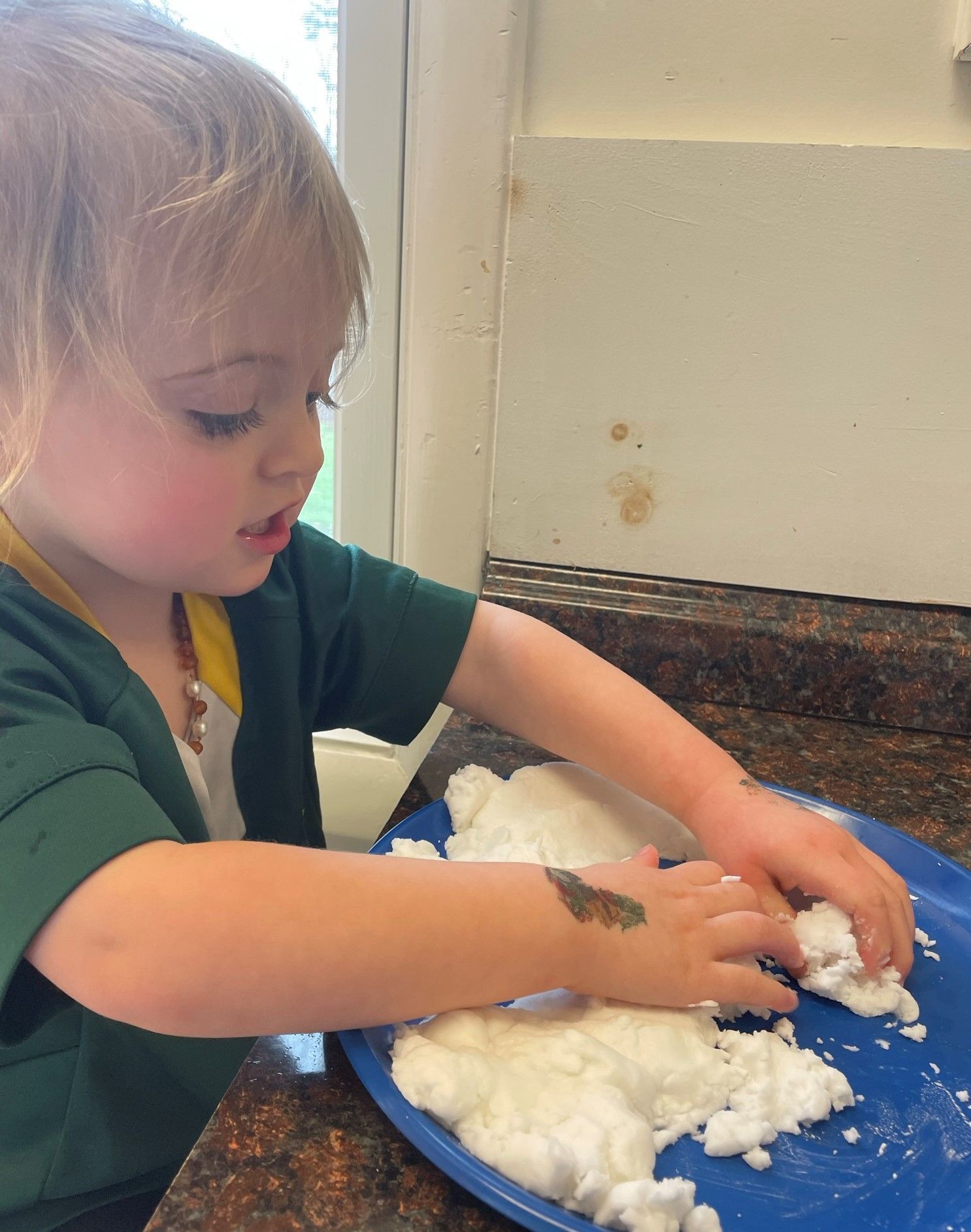 Montessori child is wprlong with snow on a blue plate.