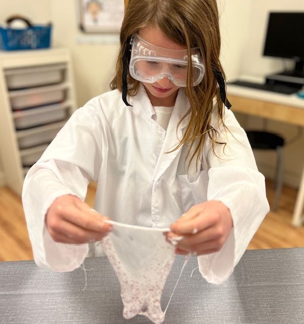 Montessori child wearing goggles and a lab coat