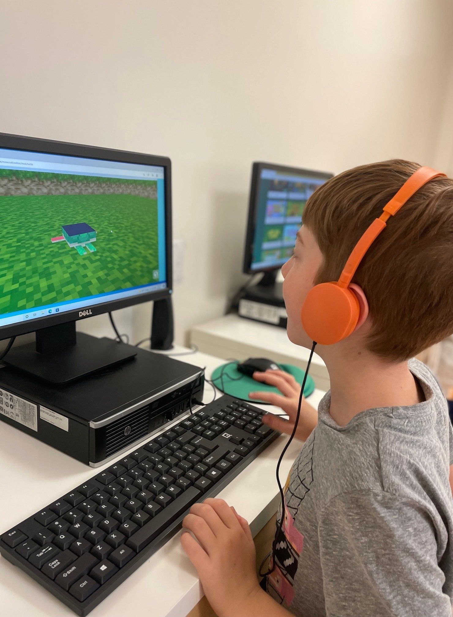 Montessori childr wearing headphones is playing a video game on a computer.