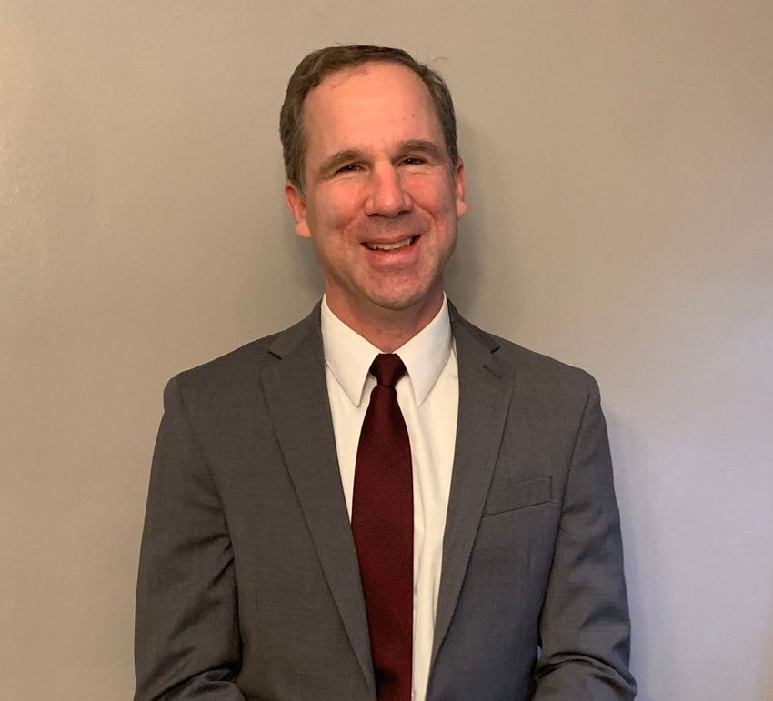 A man in a suit and tie is standing in front of a red curtain.