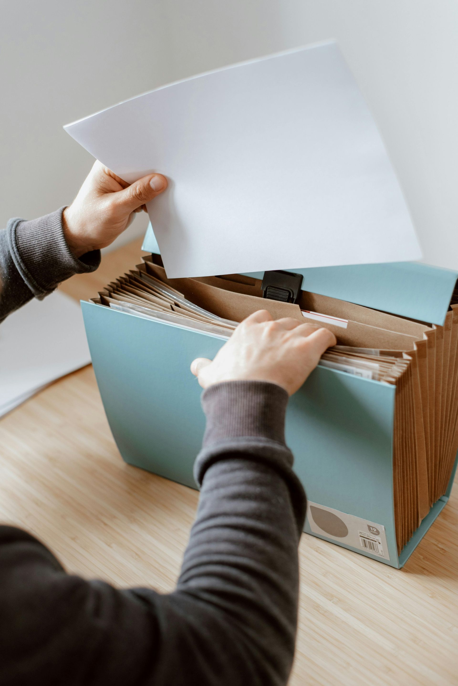 A person is taking a piece of paper out of a filing cabinet.