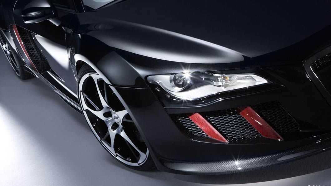 A close up of a black car 's headlight on a white surface.