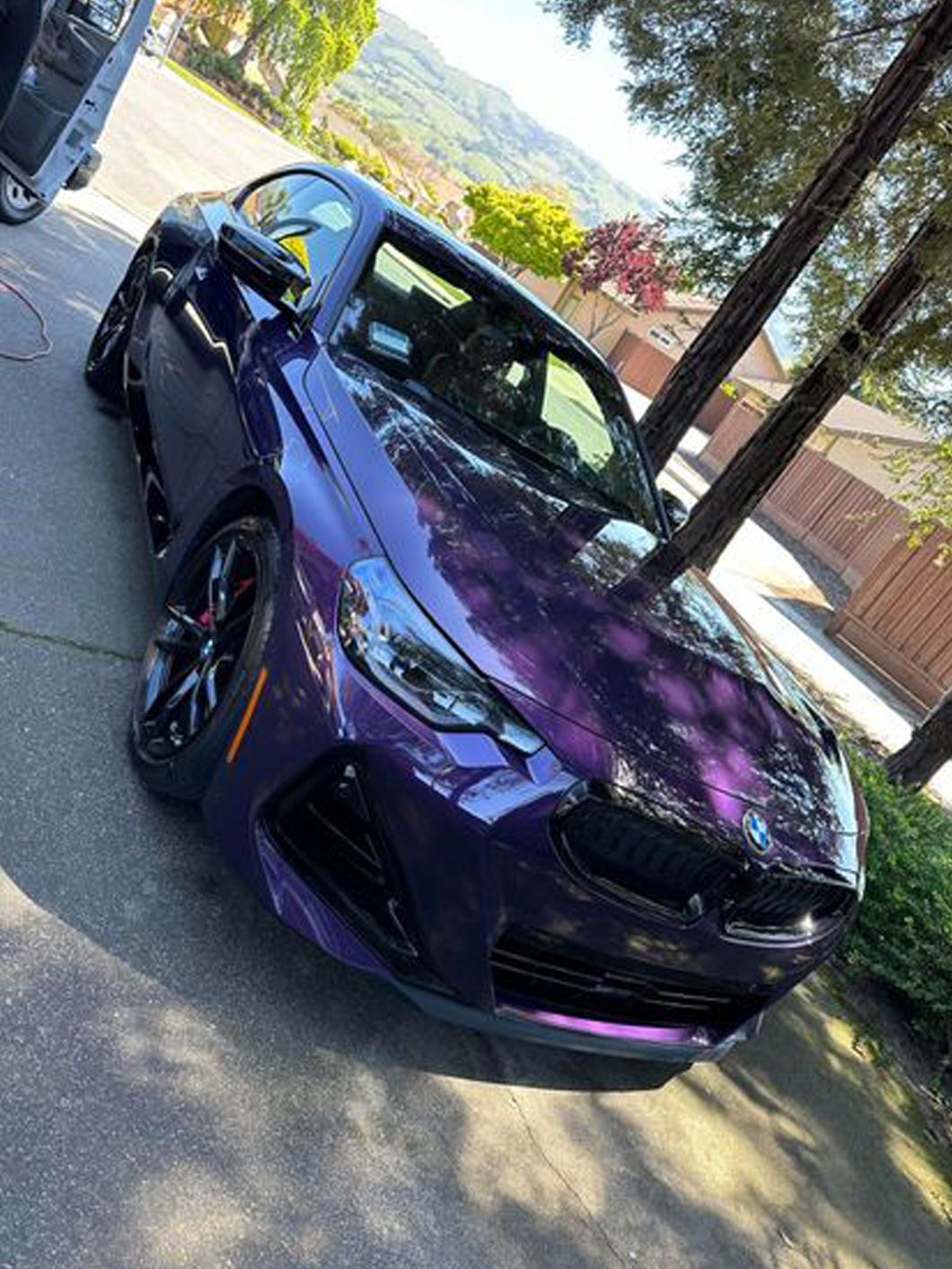 A purple bmw m4 is parked on the side of the road.