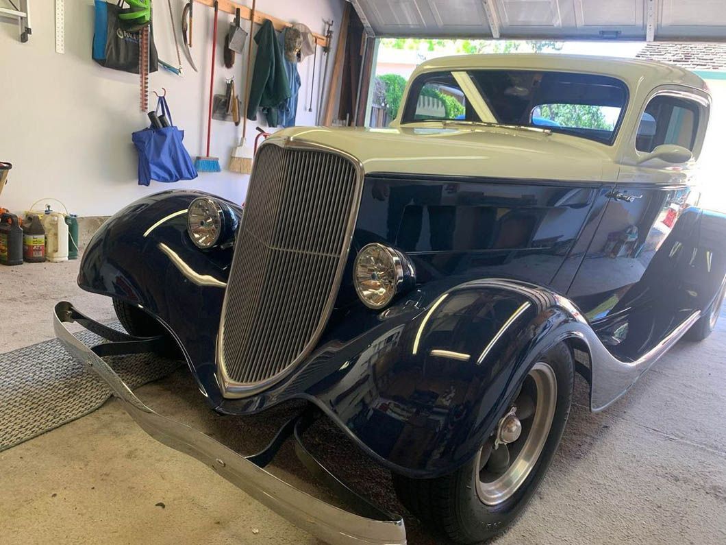A blue and white car is parked in a garage.