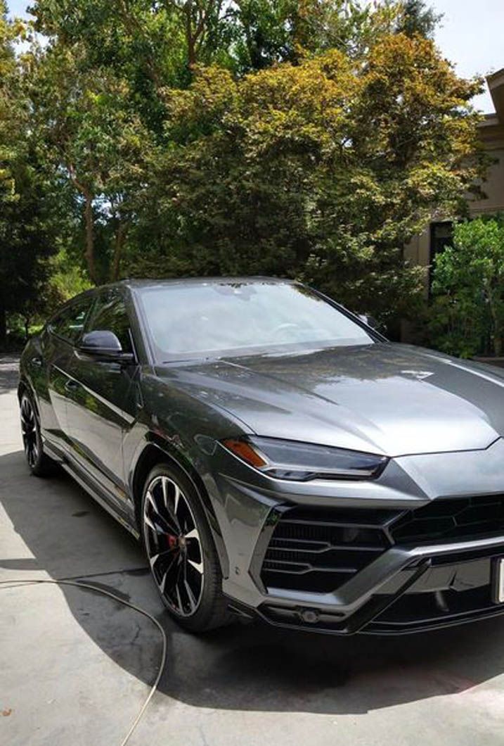 A gray lamborghini urus is parked in a driveway.