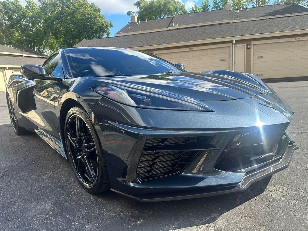 A black sports car is parked in front of a garage.