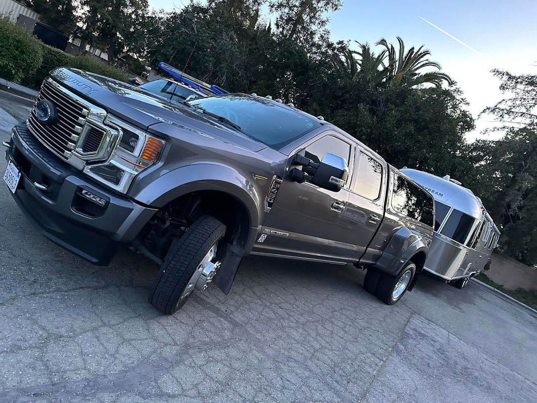 A truck is towing a trailer in a parking lot.