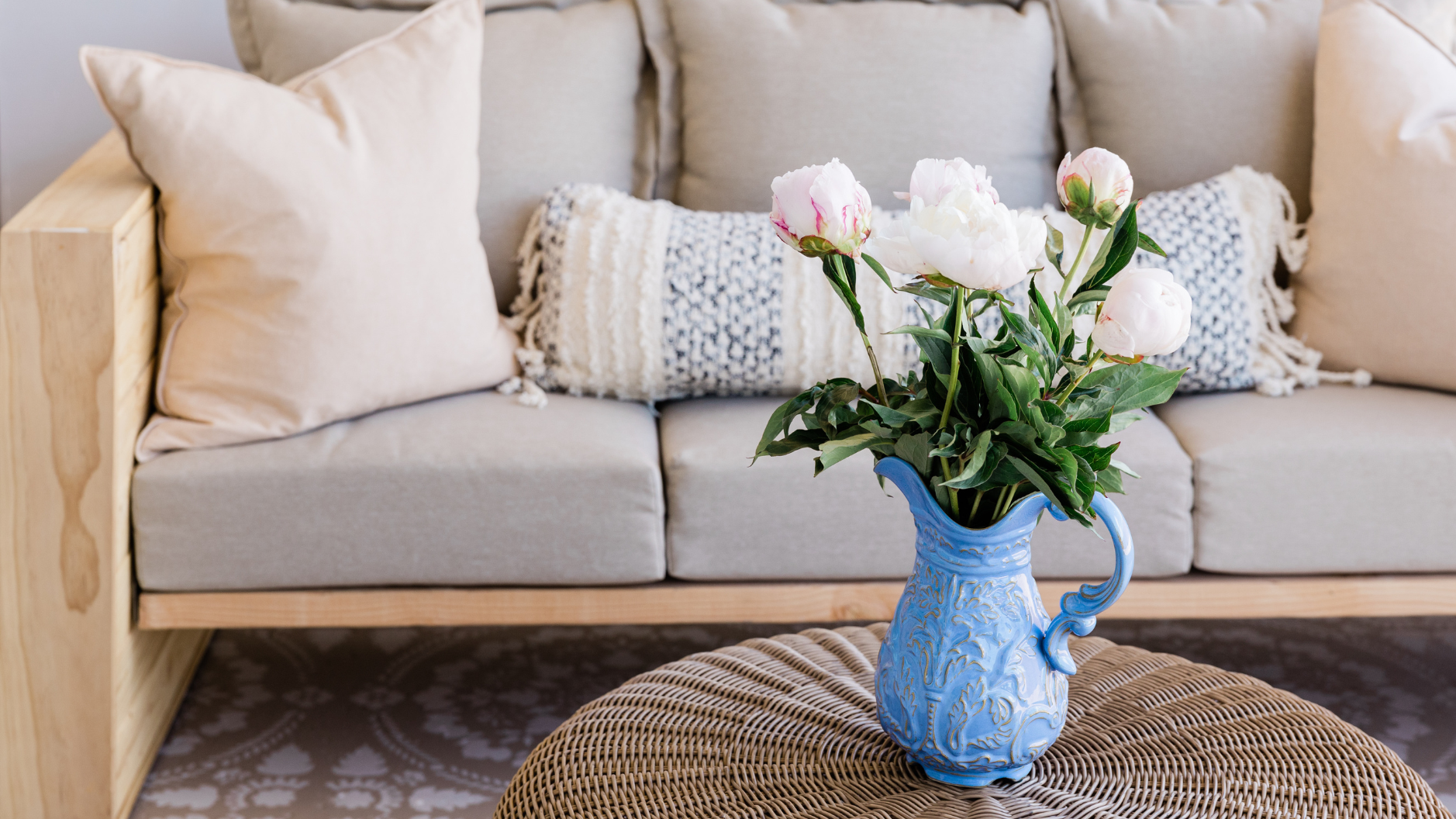 A vase of flowers is sitting on a table in front of a couch.