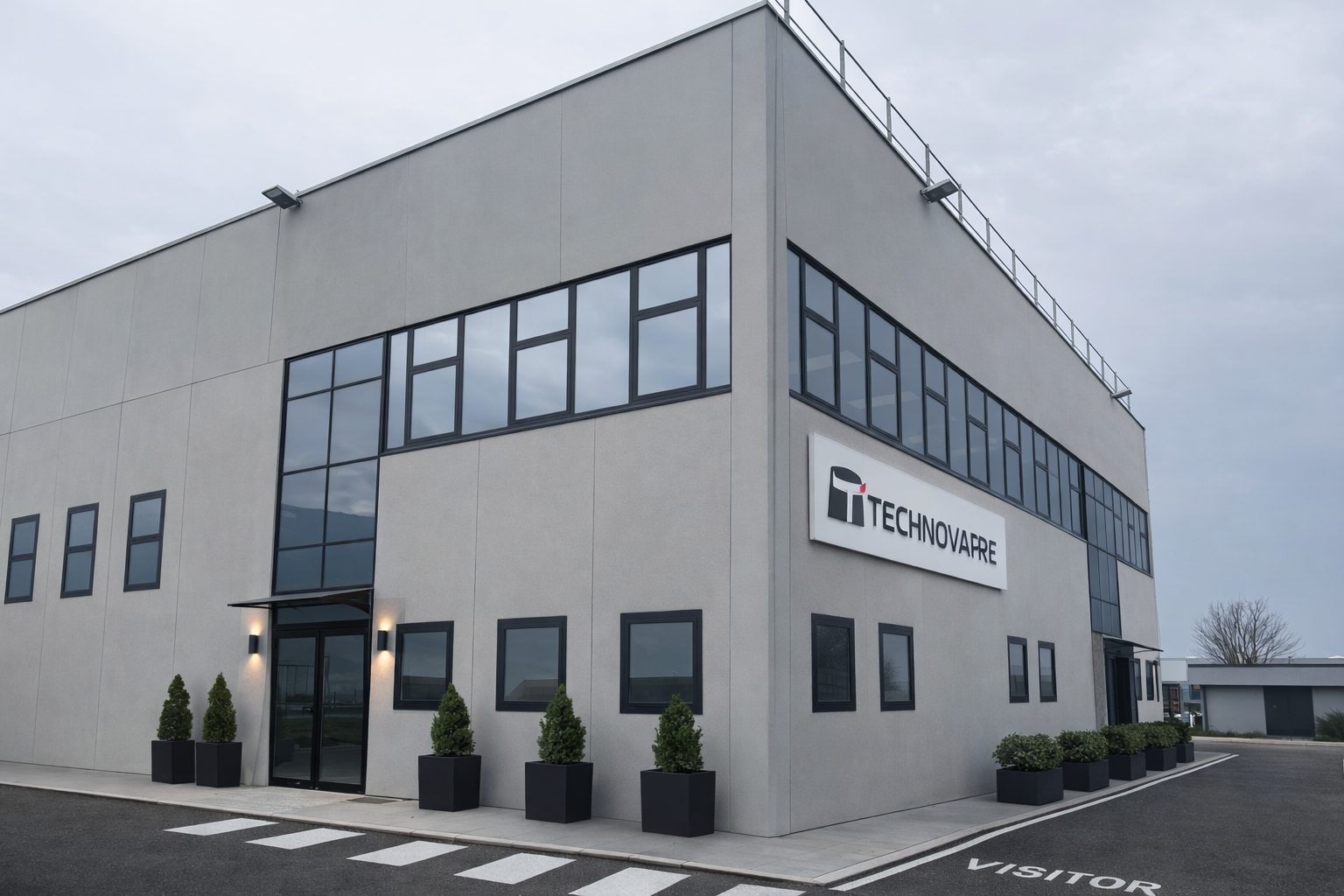 Un moderno edificio industriale a due piani di colore grigio chiaro, con ampie finestre e l'insegna 