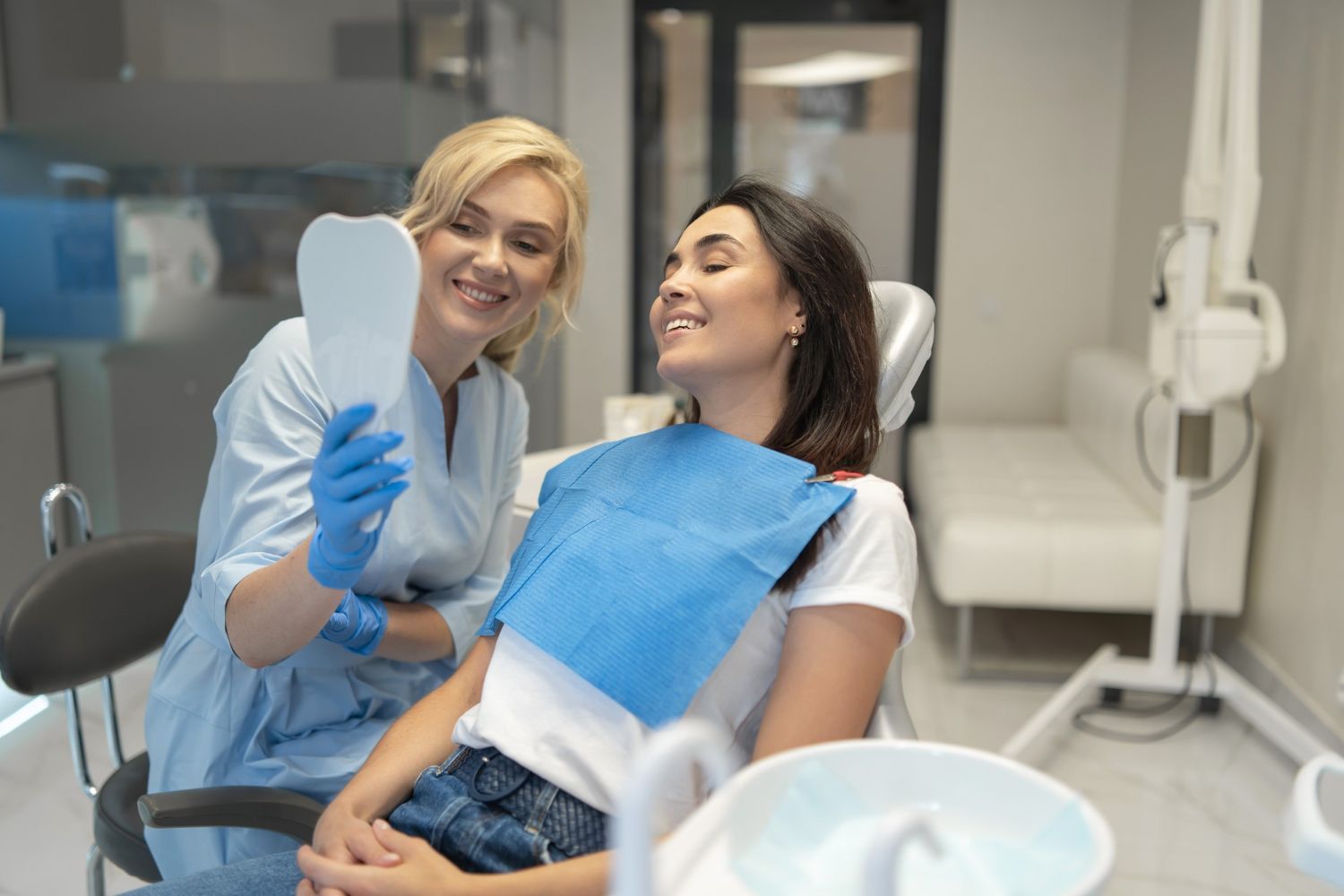 Dentist showing a patient their teeth in a mirror. They are in a dental office.