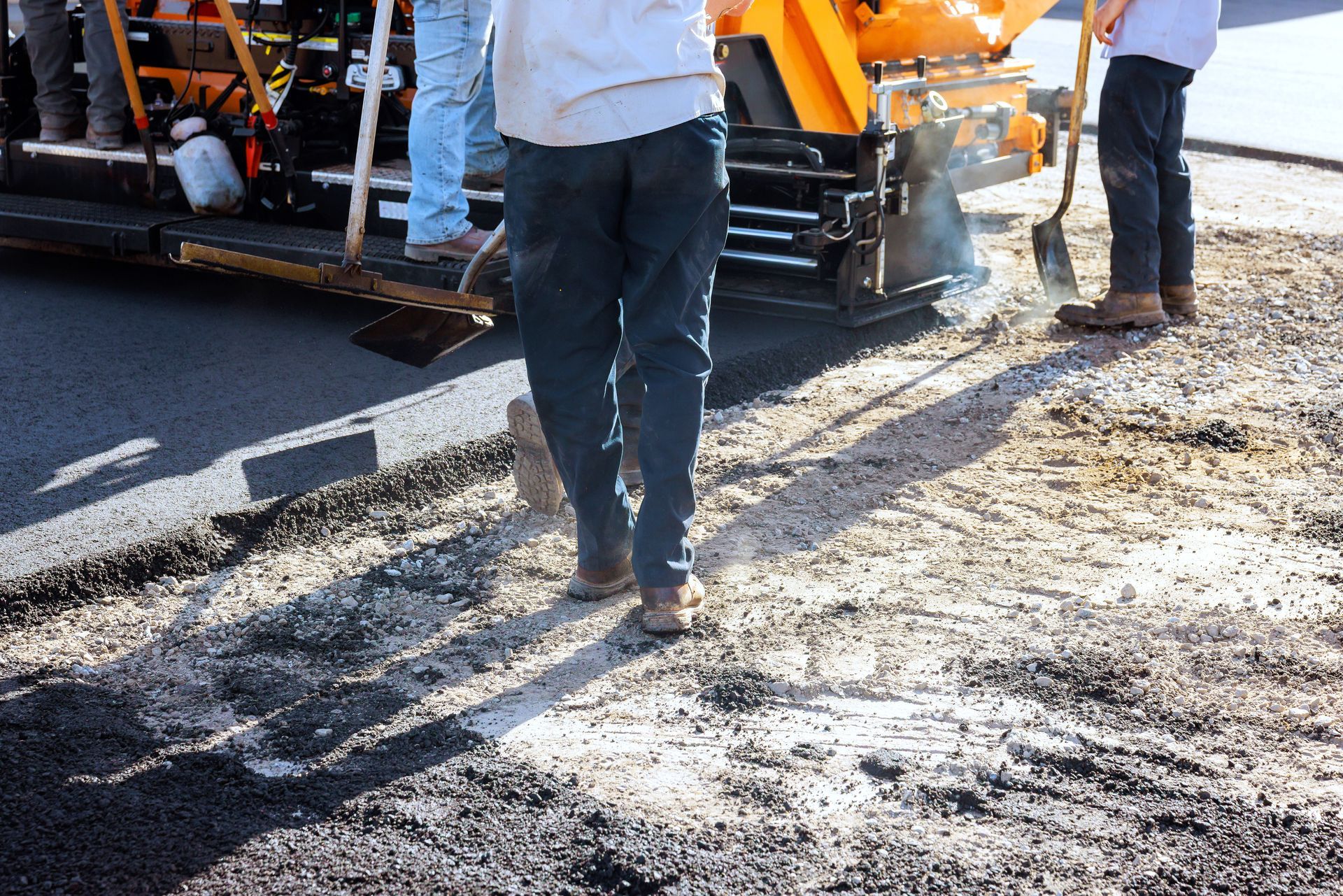 A professional team providing commercial paving services by laying fresh asphalt on a road.