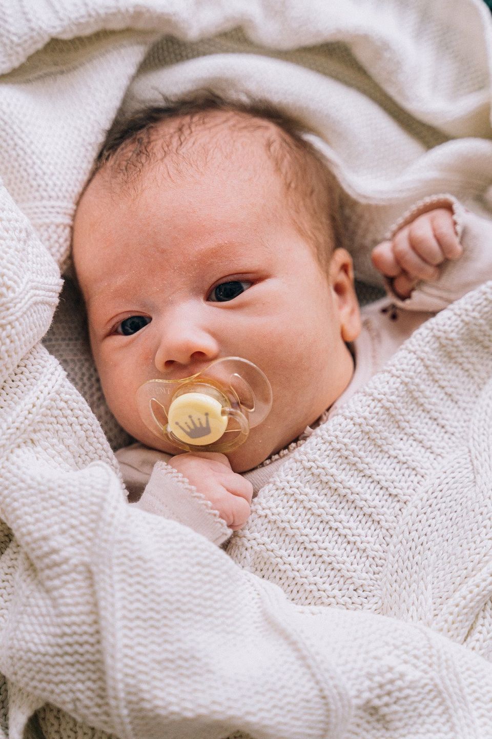 baby lying on bed with pacifier