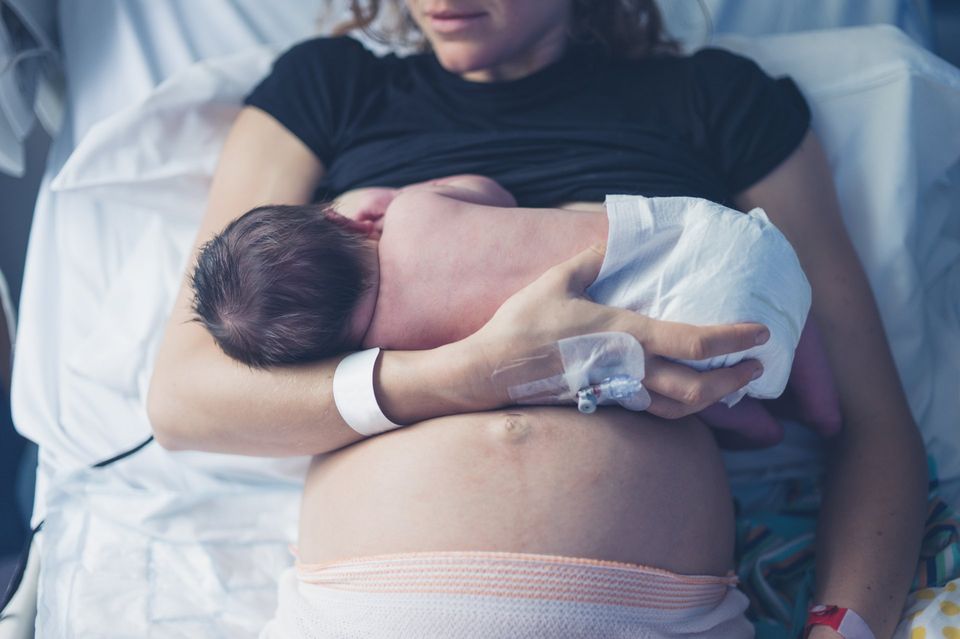 new mother holding infant on skin in hospital