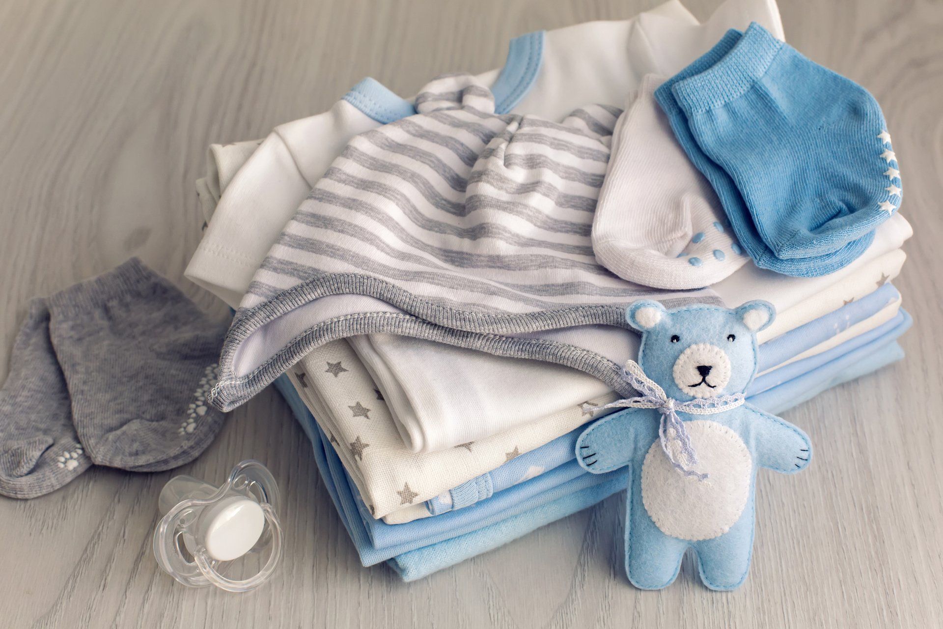 stack of newborn baby outfits and toys