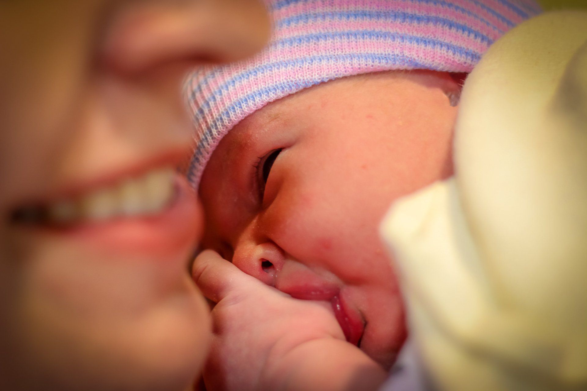 newborn baby lying on mom chest, sucking thumb