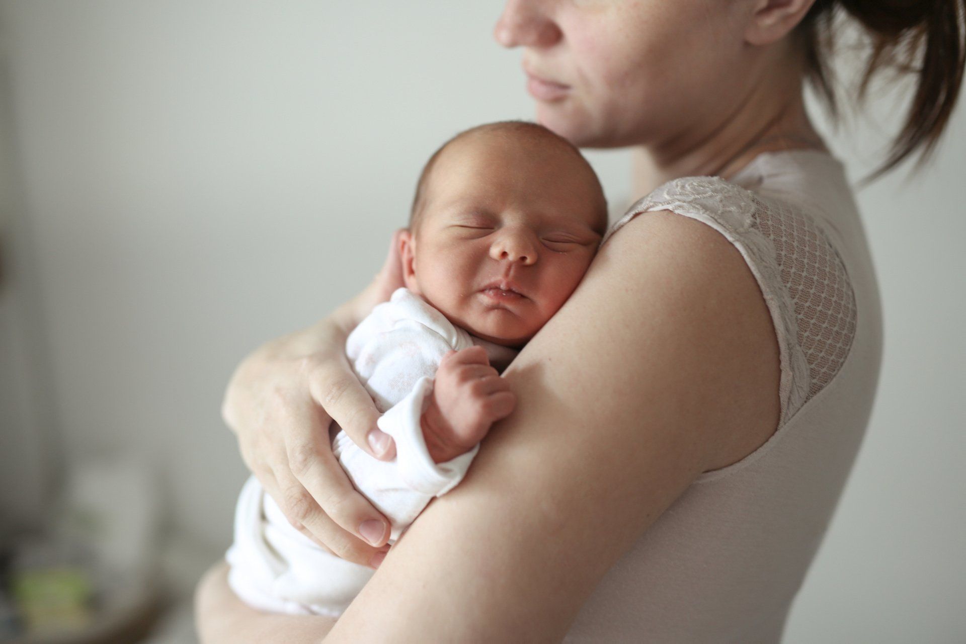 mom holding newborn baby against chest