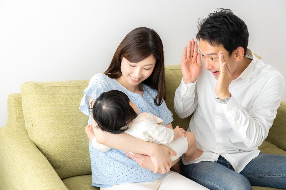 parents playing peek a boo with baby
