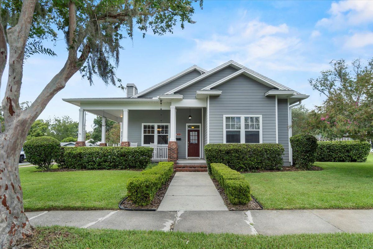 Gray house with porch, walkway, and well-manicured lawn.