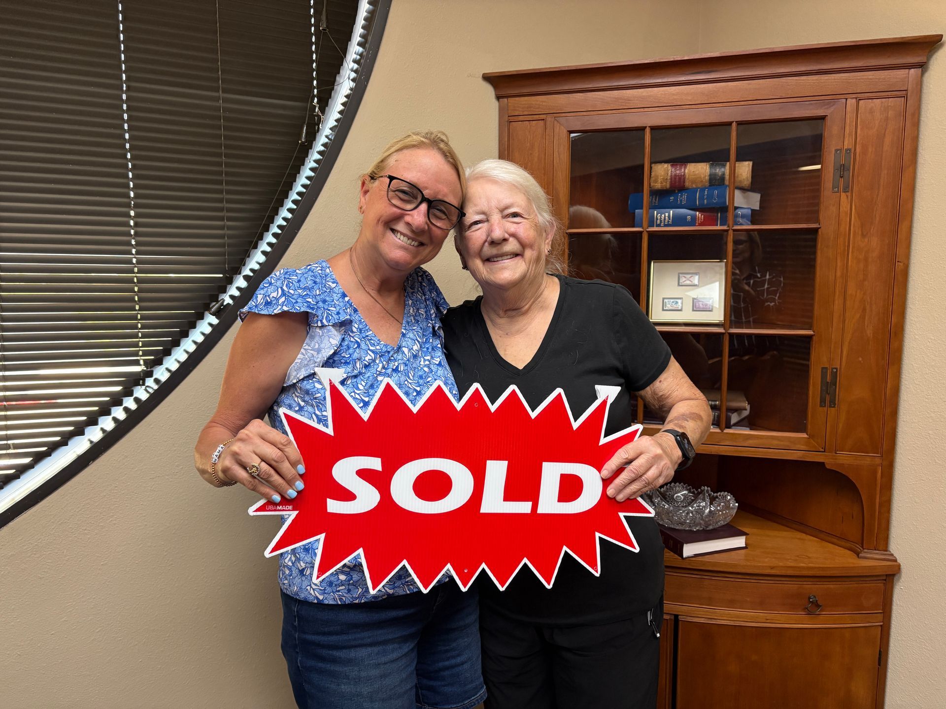 Two women smiling, holding a 
