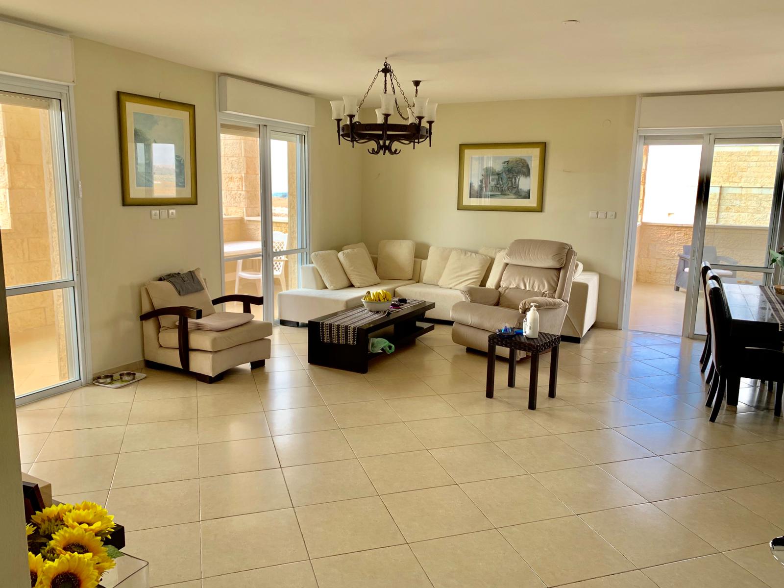 סלון עם ספה, כיסאות, שולחן קפה ונברשת.