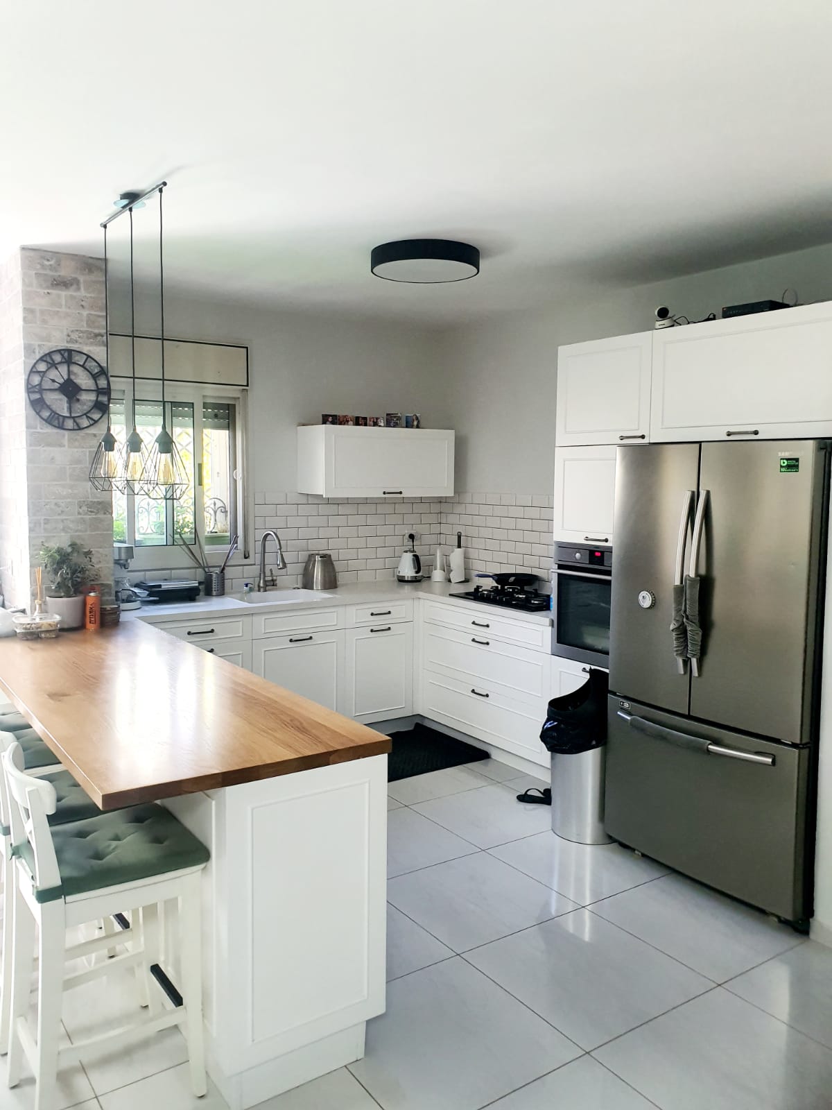 מטבח עם ארונות לבנים ומקרר נירוסטה.