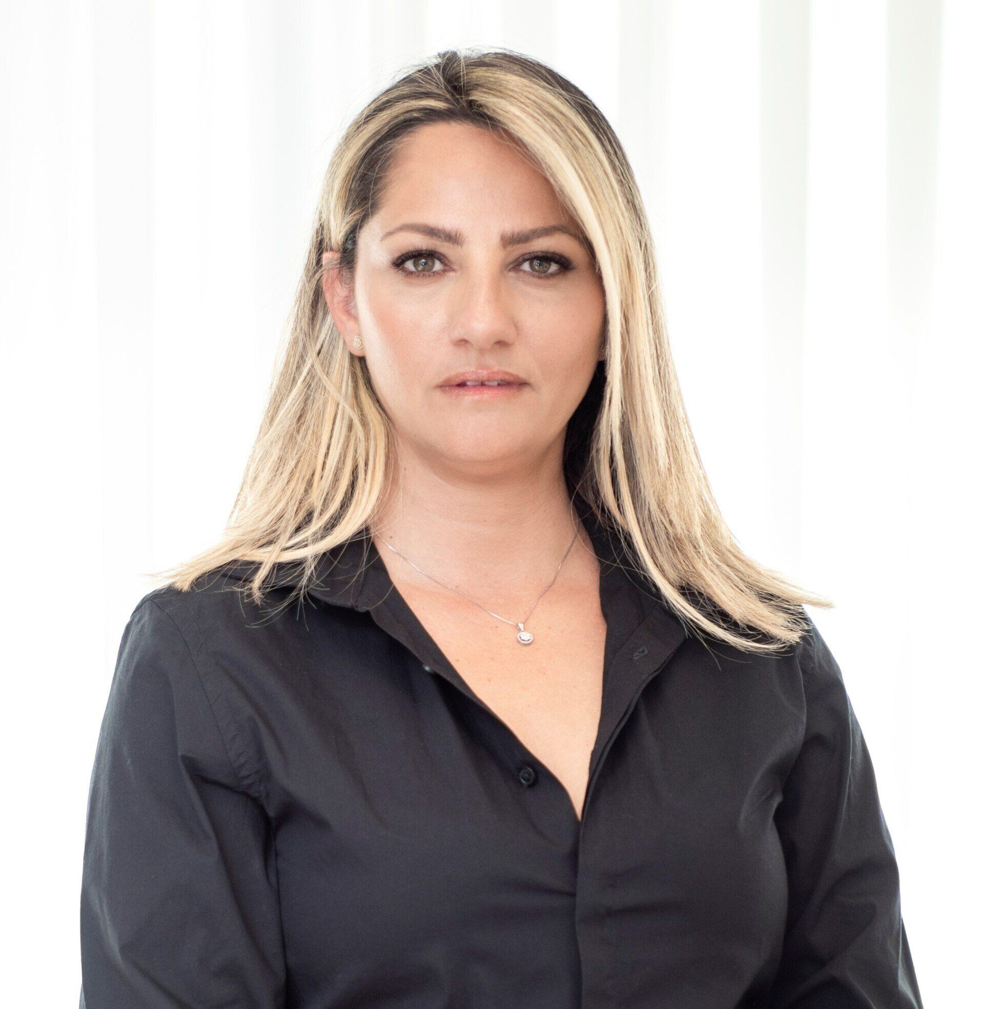 האישה לובשת חולצה שחורה ושרשרת.