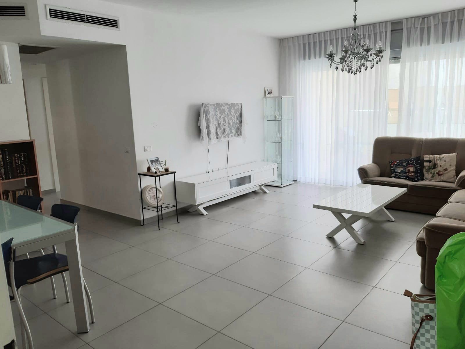 סלון עם ספה, שולחן, כיסאות וטלוויזיה.