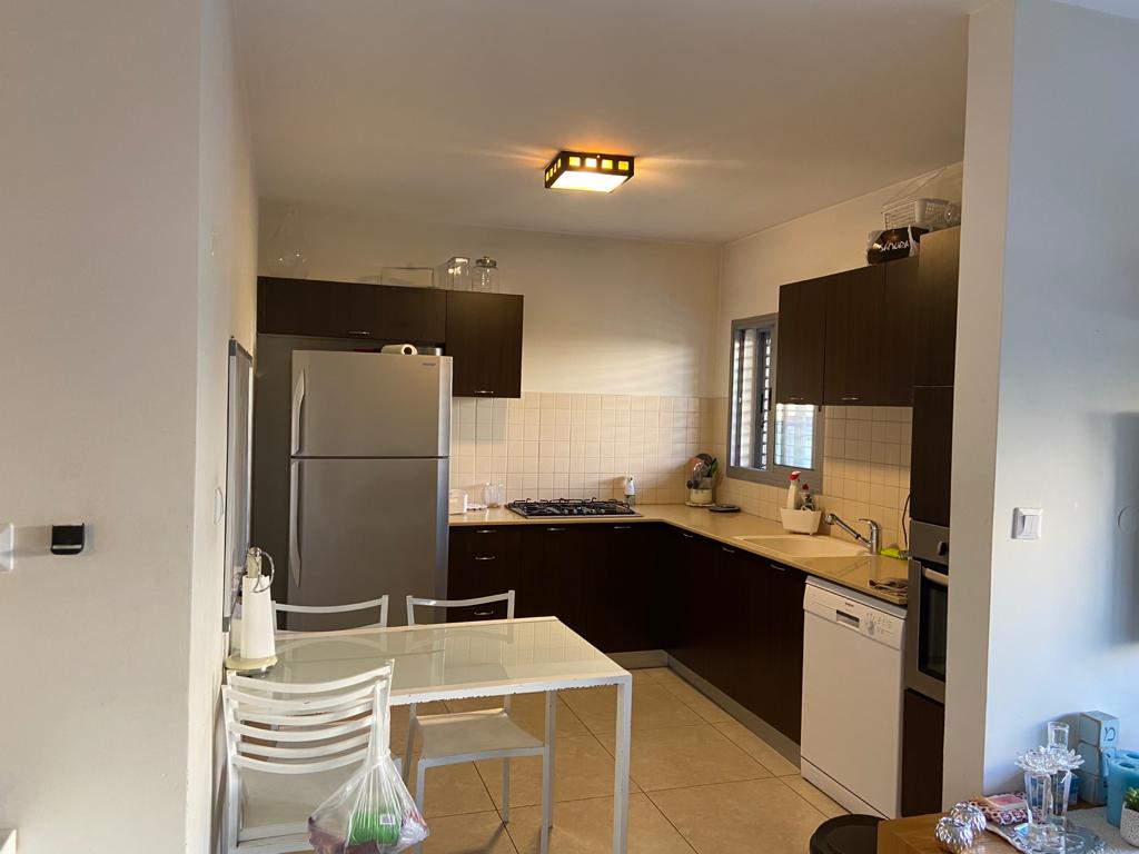 מטבח עם שולחן וכיסאות ומקרר.