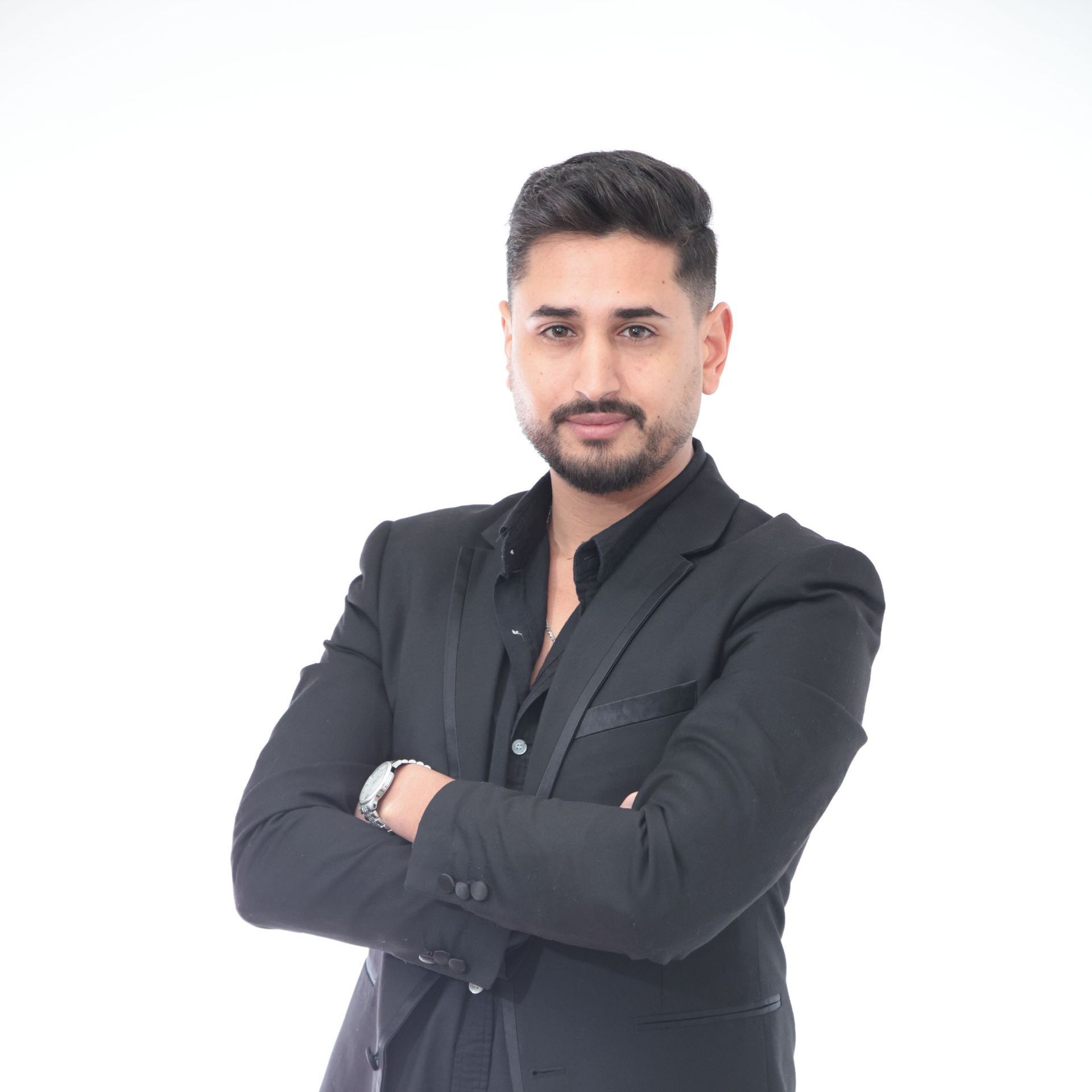 גבר בחליפה שחורה עומד בזרועותיו שלובות