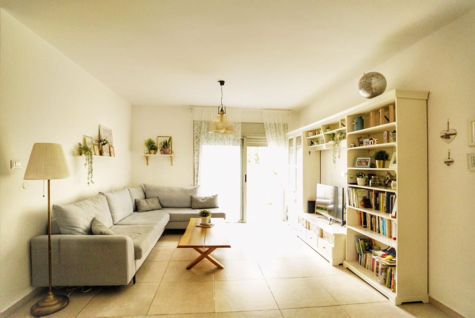 סלון עם ספה, שולחן קפה, מדף ספרים וטלוויזיה.