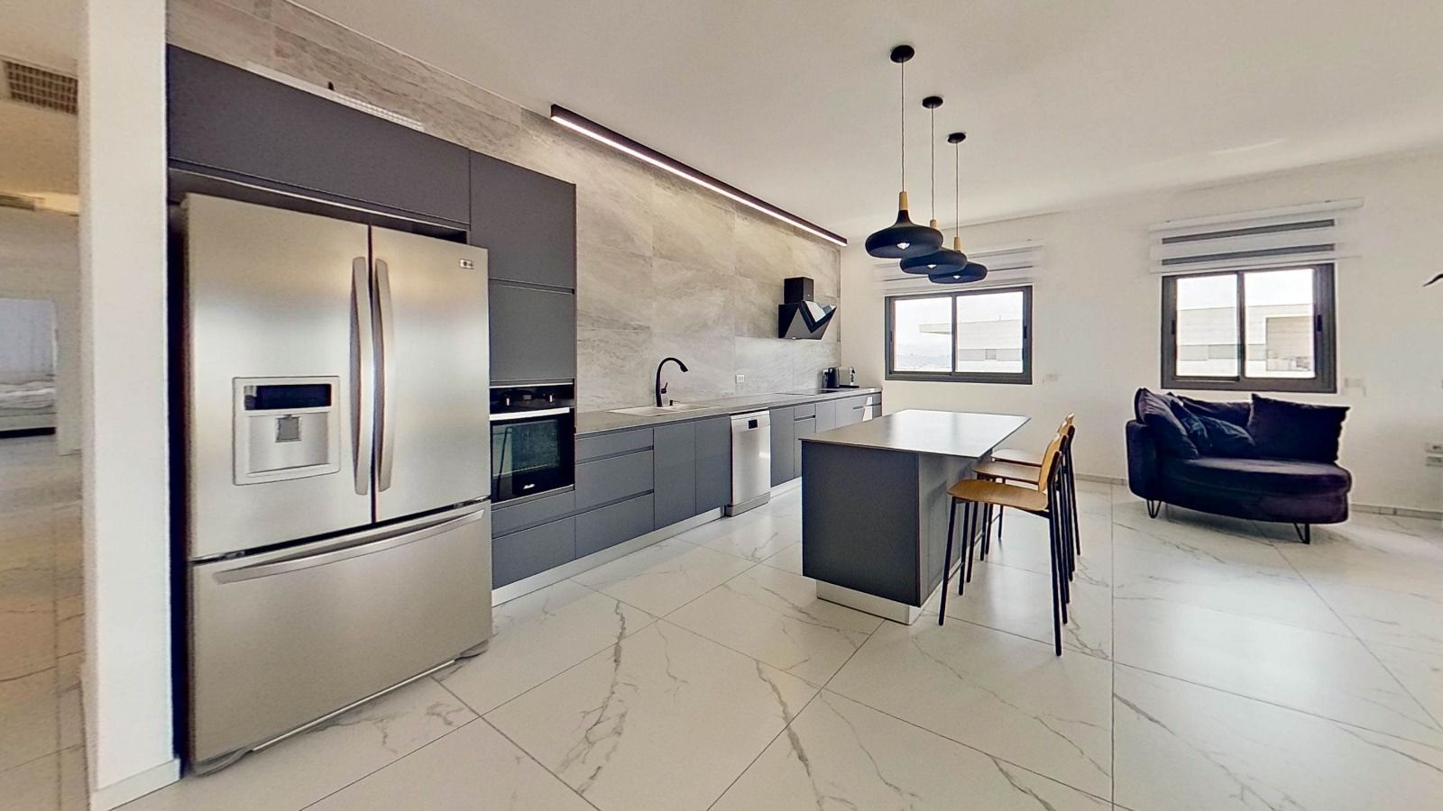 מטבח עם מקרר נירוסטה וספה שחורה