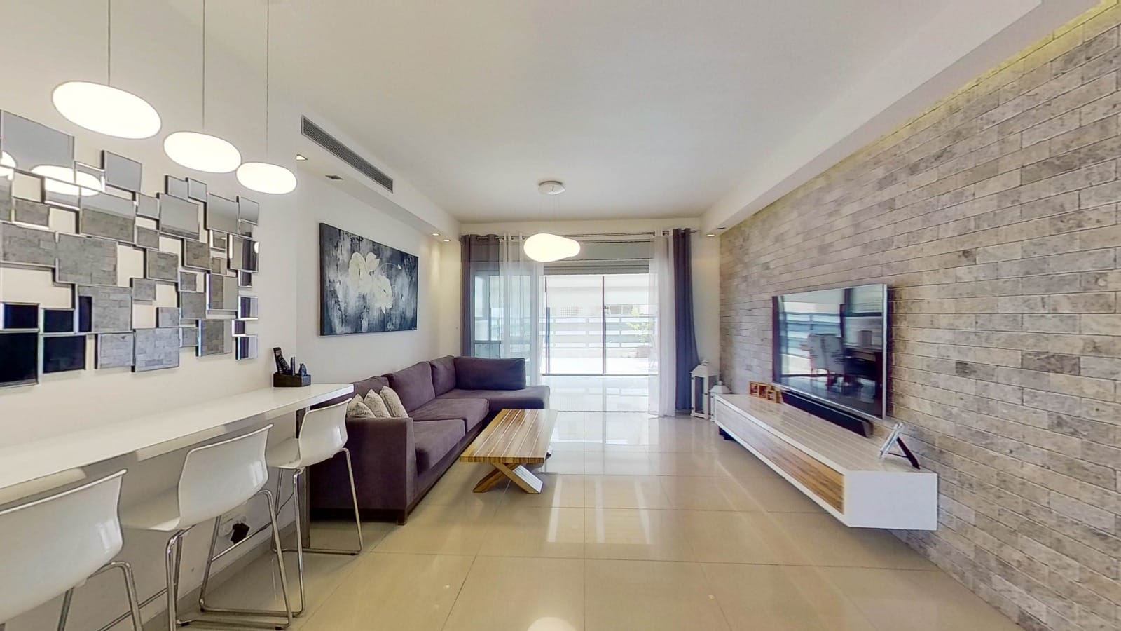 סלון עם ספה, טלוויזיה וקיר לבנים.