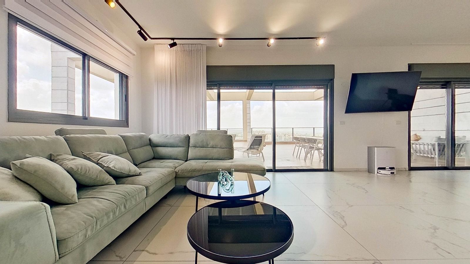 סלון עם ספה, שני שולחנות וטלוויזיה בעלת מסך שטוח.