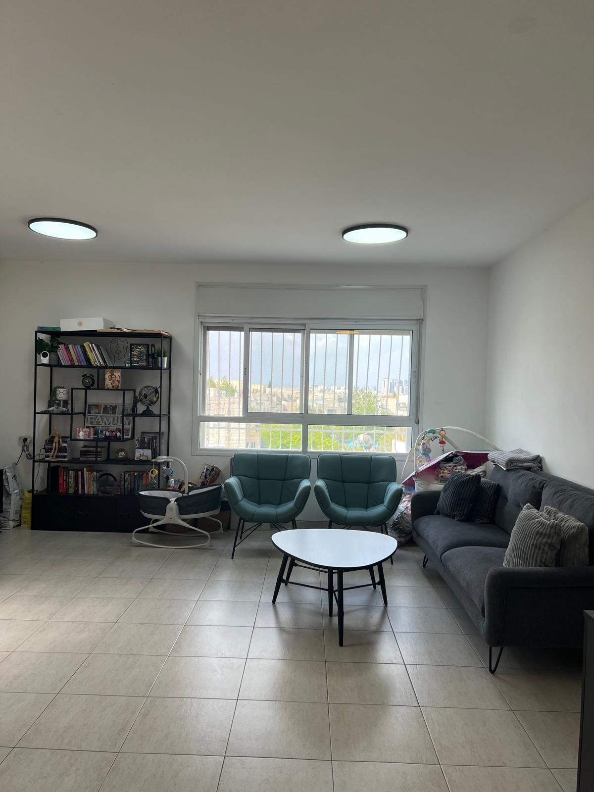 סלון עם ספה, כיסאות, שולחן קפה ומדף ספרים.